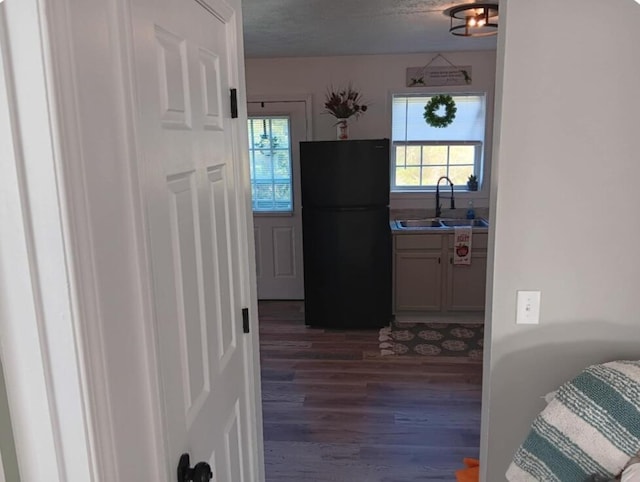 kitchen featuring black fridge, sink, dark wood-type flooring, and a textured ceiling