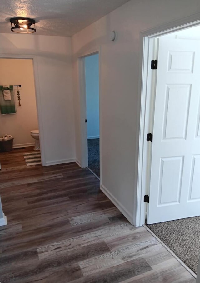 hallway featuring dark wood-type flooring and a textured ceiling