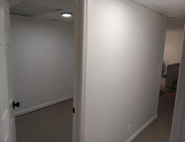 hallway featuring baseboards and a paneled ceiling