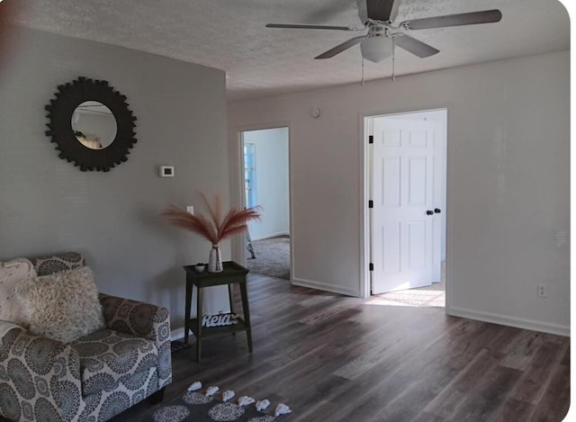 sitting room with ceiling fan, dark hardwood / wood-style flooring, and a textured ceiling