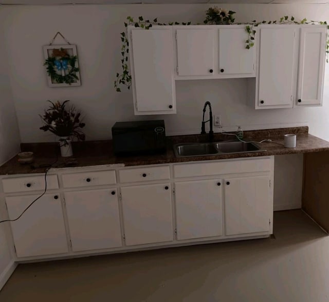 kitchen with white cabinets, dark countertops, and a sink