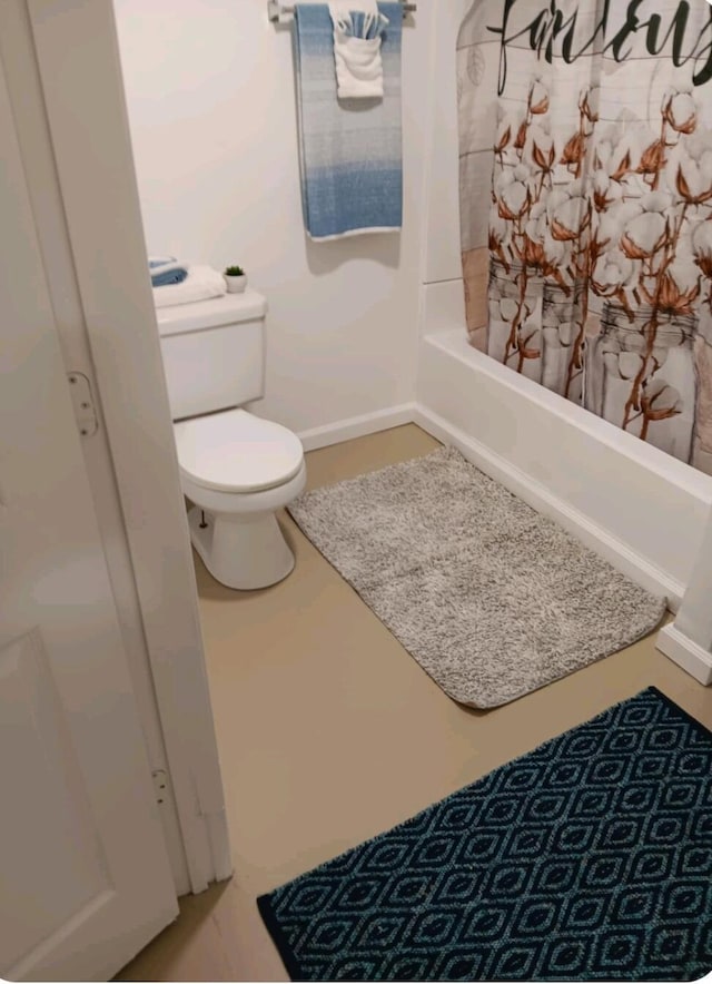 bathroom featuring baseboards, toilet, and shower / tub combo