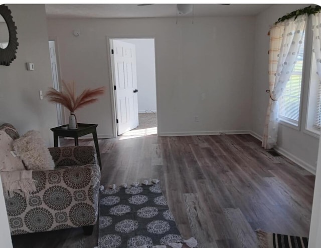 living area featuring baseboards, ceiling fan, and wood finished floors