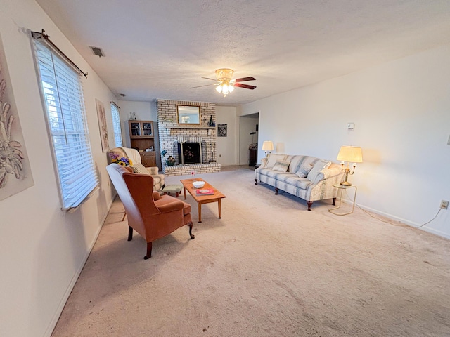 carpeted living room with ceiling fan, a textured ceiling, and a brick fireplace