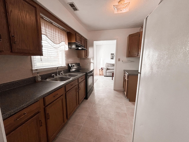 kitchen featuring white refrigerator, sink, a textured ceiling, black / electric stove, and light tile patterned flooring