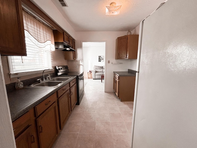 kitchen featuring a textured ceiling, stainless steel electric range, light tile patterned flooring, and sink