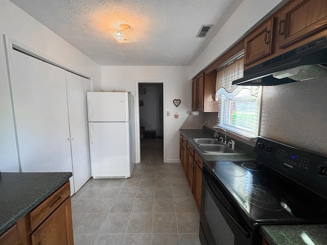 kitchen featuring black range with electric stovetop, sink, white fridge, a textured ceiling, and light tile patterned flooring