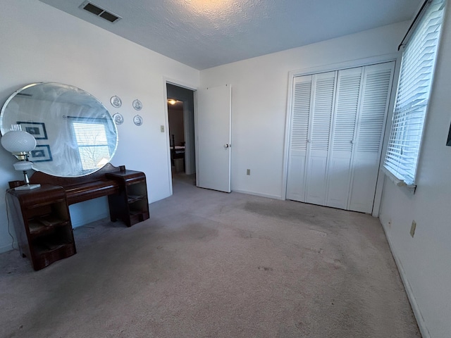 carpeted bedroom with a textured ceiling and a closet