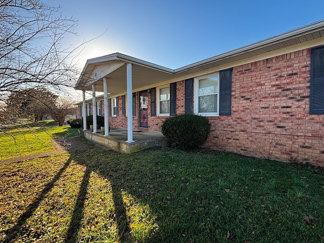 view of side of home with a lawn and covered porch