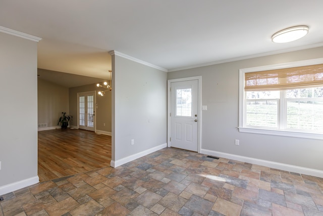 foyer featuring stone finish flooring, ornamental molding, an inviting chandelier, and baseboards