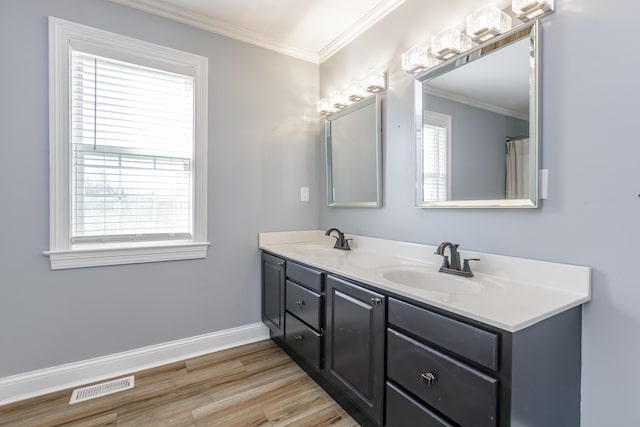 bathroom featuring crown molding, visible vents, a sink, and wood finished floors