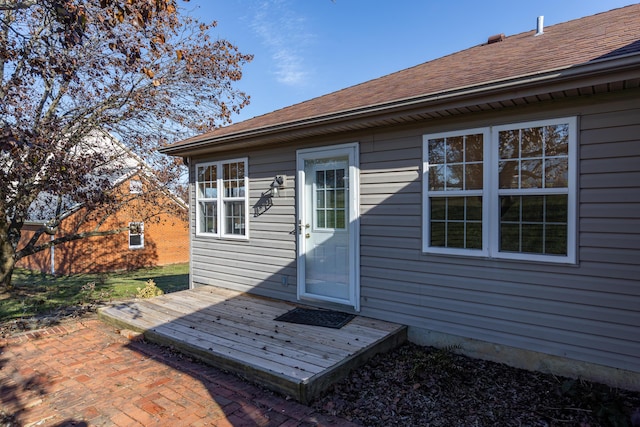 exterior space with roof with shingles and a wooden deck