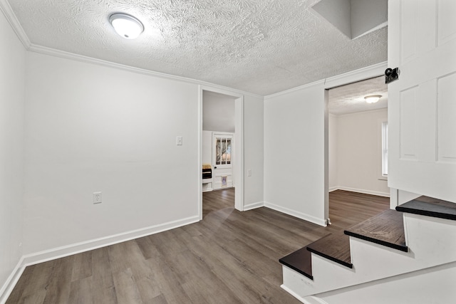 spare room with hardwood / wood-style floors, a textured ceiling, and ornamental molding