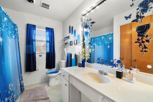 bathroom with toilet, tile patterned flooring, tile walls, and vanity