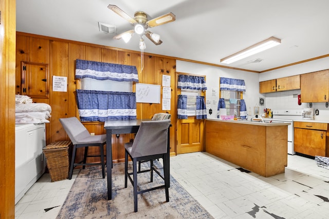 kitchen with white electric range oven, kitchen peninsula, ornamental molding, ceiling fan, and a breakfast bar area