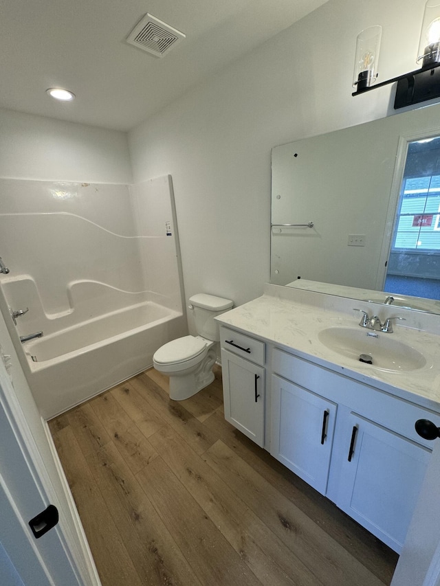 full bathroom with hardwood / wood-style floors, vanity,  shower combination, and toilet