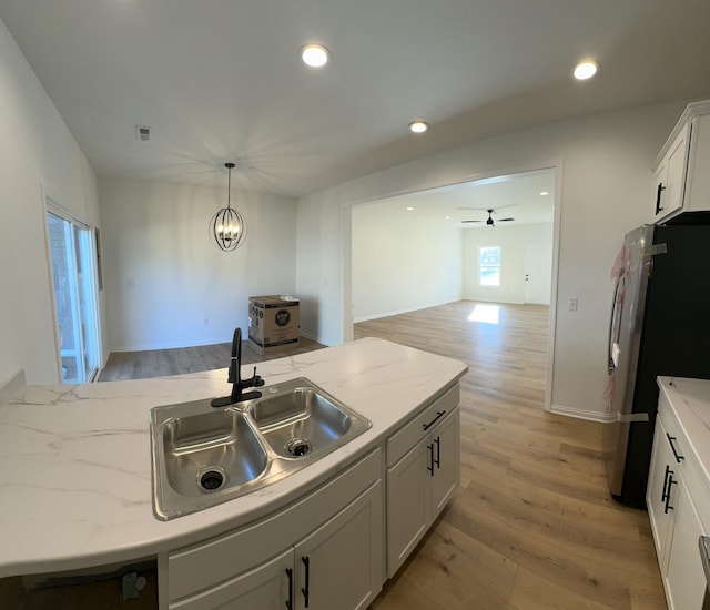 kitchen with stainless steel refrigerator, white cabinetry, sink, and light hardwood / wood-style floors