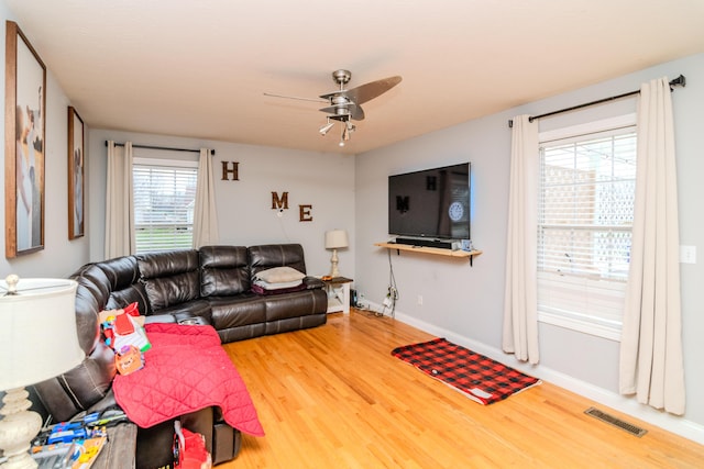 living area with visible vents, ceiling fan, baseboards, and wood finished floors