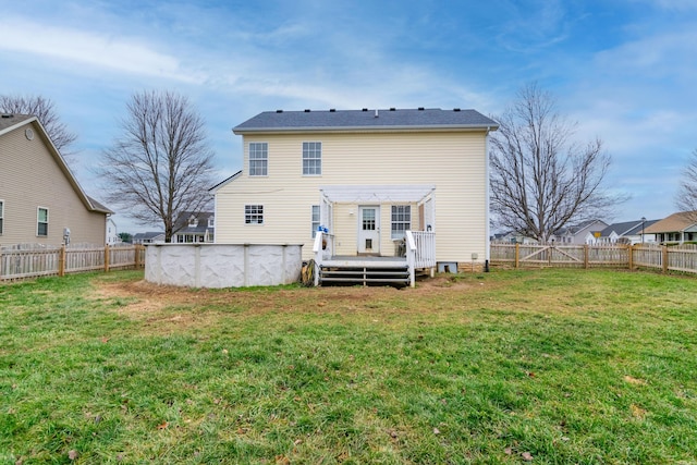 back of property with a fenced backyard, a lawn, a fenced in pool, and a wooden deck