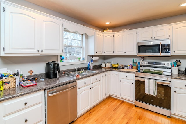 kitchen featuring light wood-type flooring, white cabinetry, appliances with stainless steel finishes, and a sink