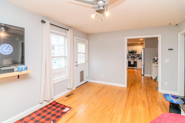 doorway to outside with ceiling fan, light wood-type flooring, visible vents, and baseboards