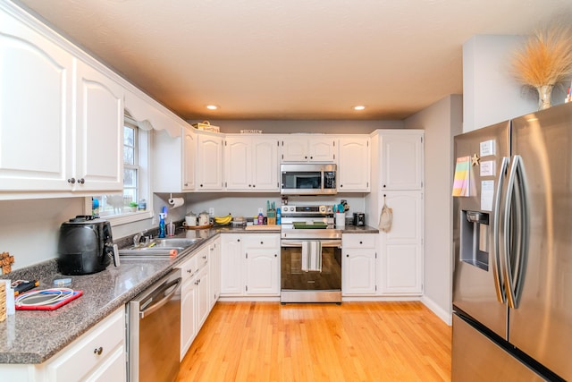 kitchen with appliances with stainless steel finishes, light wood-type flooring, and white cabinets