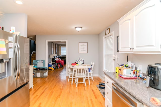 kitchen featuring baseboards, stainless steel appliances, light countertops, light wood-style floors, and white cabinetry