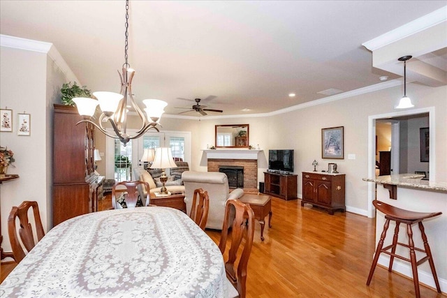 dining area with ceiling fan with notable chandelier, light hardwood / wood-style floors, and ornamental molding