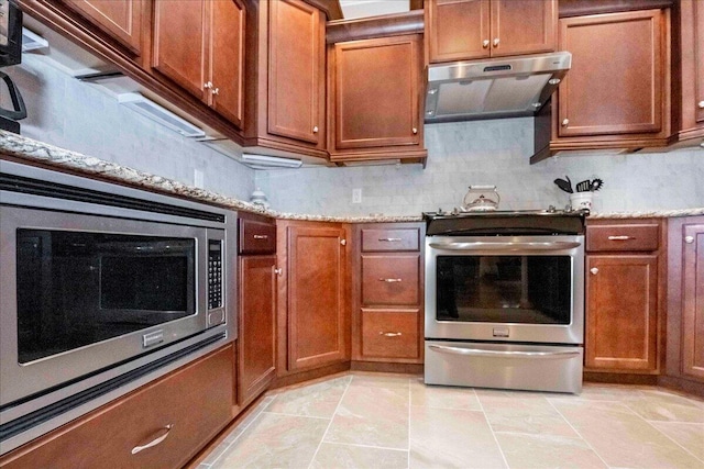 kitchen featuring backsplash, light stone counters, range hood, and appliances with stainless steel finishes