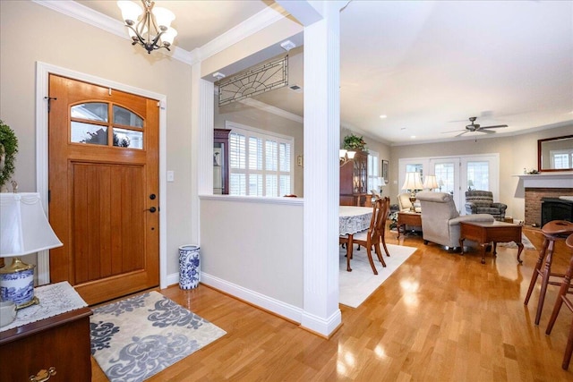 foyer entrance with ceiling fan with notable chandelier, light hardwood / wood-style flooring, and ornamental molding