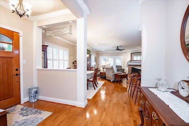 foyer featuring crown molding, a healthy amount of sunlight, ceiling fan with notable chandelier, and light wood-type flooring