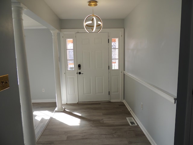 foyer entrance with dark hardwood / wood-style flooring, ornate columns, and a healthy amount of sunlight