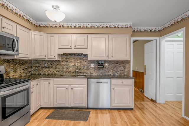 kitchen with sink, stainless steel appliances, decorative backsplash, white cabinets, and light wood-type flooring