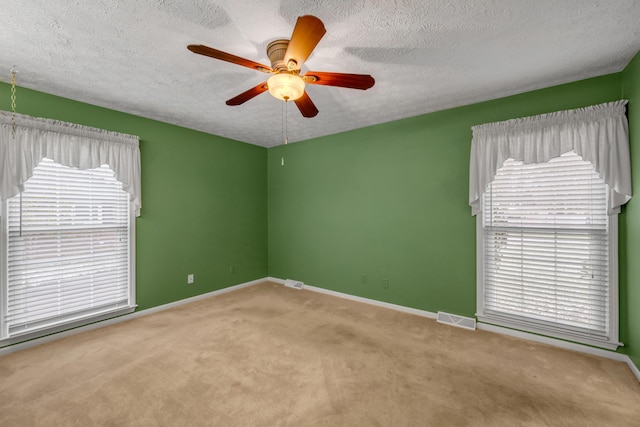 carpeted spare room featuring ceiling fan and a textured ceiling