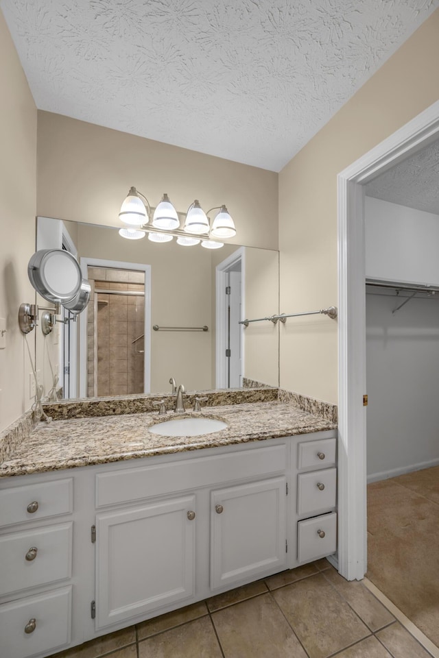 bathroom with tile patterned floors, vanity, and a textured ceiling