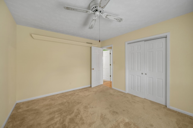 unfurnished bedroom featuring ceiling fan, light carpet, and a closet