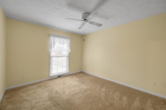 spare room with ceiling fan, light colored carpet, and a textured ceiling