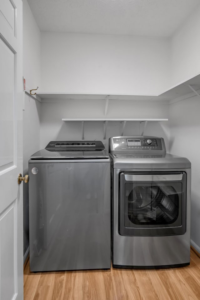 washroom with light hardwood / wood-style floors and washing machine and dryer