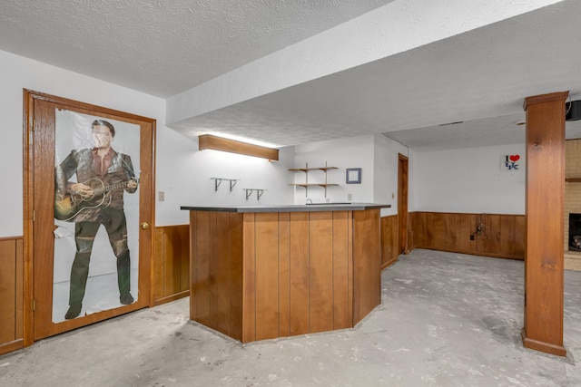 bar featuring wood walls and a textured ceiling