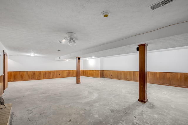 basement with wooden walls and a textured ceiling