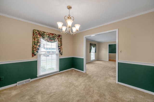 spare room featuring ornamental molding, carpet floors, and a chandelier