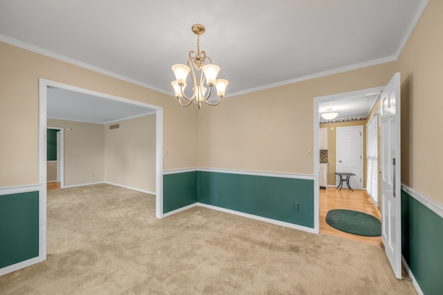 carpeted empty room with a notable chandelier and ornamental molding