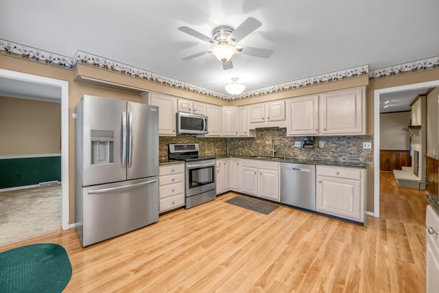 kitchen featuring ceiling fan, sink, tasteful backsplash, appliances with stainless steel finishes, and light wood-type flooring