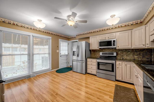 kitchen featuring ceiling fan, light hardwood / wood-style flooring, backsplash, dark stone countertops, and appliances with stainless steel finishes