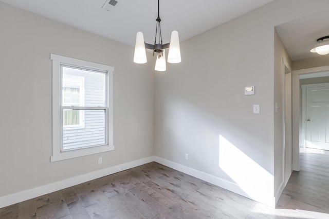 empty room featuring a notable chandelier and light hardwood / wood-style floors