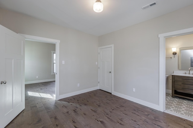 unfurnished bedroom with hardwood / wood-style floors, connected bathroom, and sink