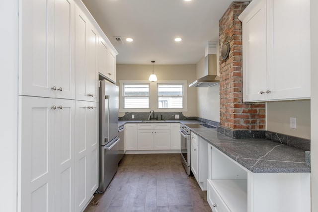 kitchen with white cabinets, wall chimney range hood, sink, dark hardwood / wood-style floors, and appliances with stainless steel finishes