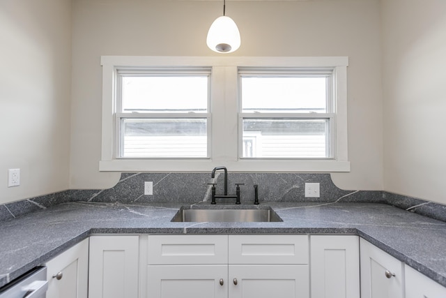 kitchen featuring white cabinetry, sink, hanging light fixtures, and stainless steel dishwasher