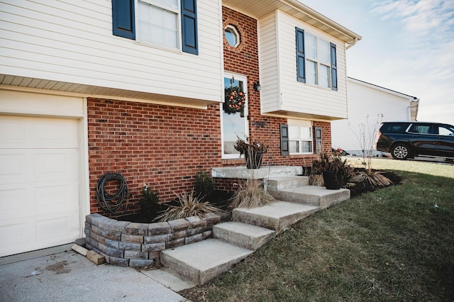 entrance to property featuring a yard and a garage