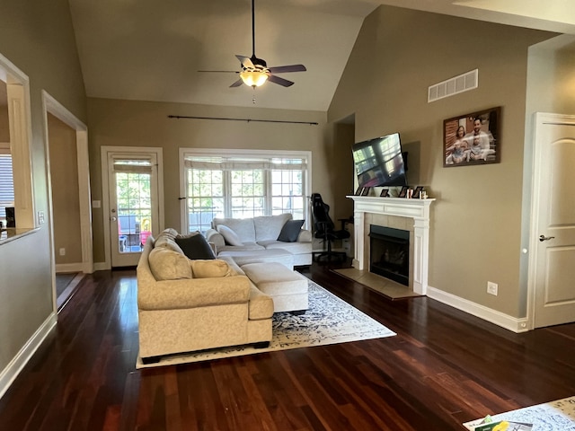 living room featuring a tile fireplace, dark hardwood / wood-style flooring, high vaulted ceiling, and ceiling fan